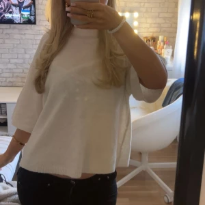 Vit stickad tröja med trekvartsärm - Säljer en vit stickad tröja med trekvartsärm och avslappnad passform. Tröjan har en enkel design med ribbad kant vid hals och nederdel, perfekt för dig som gillar en clean och chill stil.