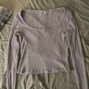 Beige ribbad topp  - Säljer en beige långärmad topp från H&M med ribbad struktur och croppad passform. Toppen har en bred, rundad urringning och är tillverkad i mjuk bomullsmix. Perfekt att styla med jeans eller kjol för en chill look🤍