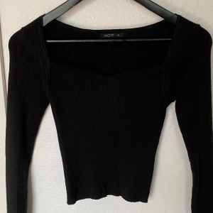 Svart ribbad långärmad topp från MOTF - Säljer en svart ribbad topp från MOTF i storlek M. Toppen har lång ärm, fyrkantig ringning och är figurnära i modellen. Perfekt att styla med jeans eller kjol för en clean look. Materialet är stretchigt och bekvämt.