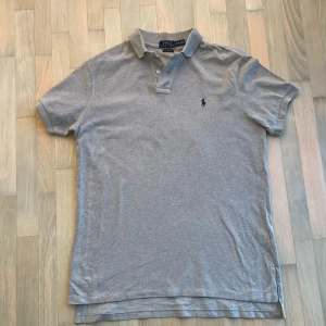 Ralph Lauren piké - Snygg grå pikétröja från Polo Ralph Lauren i storlek L. Pikén är i extremt bra skick knappt tecken på användning! Hör av dig vid minsta fundering!🤗