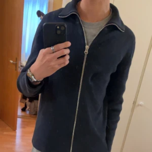 Marinblå ribbad kofta från Ljung - Svart ribbad kofta från Ljung by Marcus Larsson i storlek S.  Den är nästintill oanvänd, ända deffecten är ett hål under nacken/övre rygg men går att sy ihop eller ha en svart tröja under för att minska synligheten på hålet, kontakta gärna vid intresse😊🙏🏼