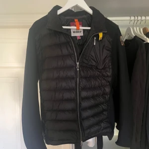 Parajumper cardigan - Svart parajumper cardigan i storlek S. Köpt på NK för 4000, alltså helt äkta. Den är använd ett fåtal gånger men har inga synliga defekter, 9/10 skick. Den är varm och perfekt nu inför hösten men klarar även mildare vinterdagar. Pris kan diskuteras.