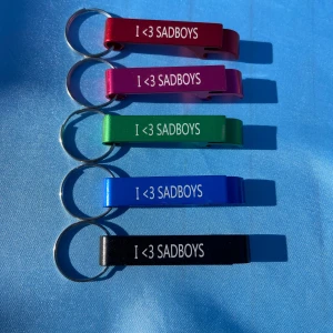 SADBOYS - bottle cap opener keychain - 1pcs ”I LOVE SADBOYS” Bottle Cap Opener Keychain. Finns i olika färger kommer att väljas SLUMPMÄSSIGT. Det går att önska sig en särskild färg men om den är slut kommer en annan skickas. Alla GTBSBE beställningar kommer med foto + sticker. Alla beställningar kommer med FREEBIES.