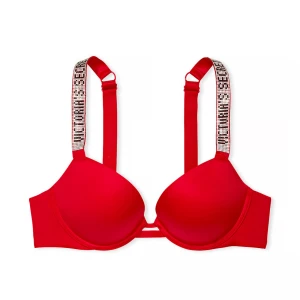 Röd push-up bh från Victoria's Secret - Säljer en snygg röd push-up bh från Victoria's Secret med glittriga axelband där det står 'Victoria's Secret' i stenar. Bh:n har vadderade kupor och justerbara band. Perfekt för dig som vill ha något extra under kläderna.