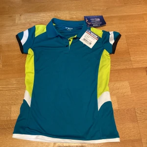 Victor blå och gul pikétröja - Badminton - Sportig pikétröja från Victor i blått, gult och vitt. Tröjan har klassisk krage, korta ärmar och knappar framtill. Perfekt för dig som gillar att sticka ut på träningen eller på badmintonbanan / tennisbanan