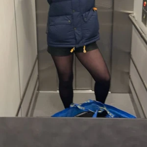 Svarta skinnshorts med fickor - Säljer ett par svarta shorts i skinnimitation med en clean look och diskreta fickor på sidorna. De är höga i midjan och har en snygg, lite loose passform. Perfekta att styla med strumpbyxor och boots för en cool vibe.