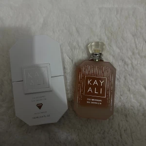 Kayali The Wedding Silk Santal - En modern parfym med inslag av sparkling champagne, white freesia, pink praline, lush nectarine, sandalwood och sugared musk. Volym: 100 ml. Perfekt för dig som vill sticka ut med en unik doftprofil. 