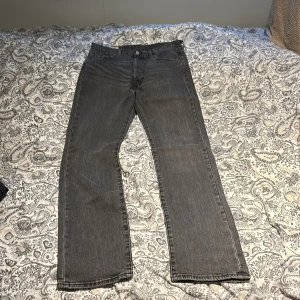 Levi's 501 svarta jeans straight fit - Säljer ett par klassiska Levi's 501 jeans i svart tvätt. Jeansen har rak passform, fem fickor och knappgylf. Ikonisk läderpatch bak i midjan och röd Levi's-tagg på bakfickan. Perfekta för en avslappnad och tidlös stil.