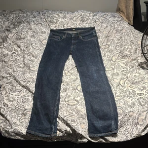 Blå jeans från BOSS med raka ben - Säljer ett par klassiska blå jeans från BOSS med raka ben och snygga kontrastsömmar. Jeansen har fem fickor, läderpatch med BOSS-logga bak och är tillverkade i slitstarkt denim. Perfekta för dig som gillar en tidlös och enkel stil.