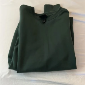 Mörkgrön sweatshirt från H&M - En stilren mörkgrön sweatshirt från H&M med klassisk rund halsringning. Tröjan är i mjuk bomull och har en enkel, clean look utan tryck eller mönster. Perfekt för dig som gillar basic och bekvämt.