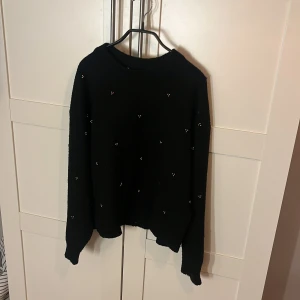 Svart stickad tröja med pärlor H&M - Svart stickad tröja från H&M i storlek S. Tröjan har långa ärmar och är dekorerad med små pärlor över hela plagget för en extra touch. Perfekt för dig som gillar en enkel men ändå snygg look.