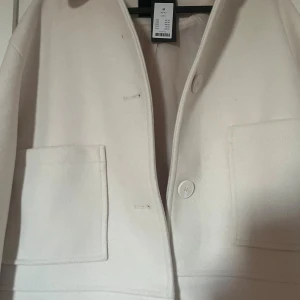 Vit kappa med stora fickor, stl M - Köpt på lager lappen är kvar aldrig använd perfekt för dig som gillar minimalistisk och clean stil. Köpt för 400