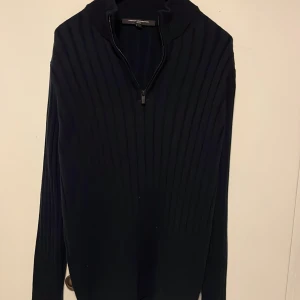 Marin blå ribbad tröja från French Connection - Säljer en mörk marinblå ribbad tröja från French Connection med half zip-dragkedja framtill. Tröjan har lång ärm, hög krage och är stickad i ett mjukt material. Perfekt för dig som gillar stilrena och klassiska plagg.