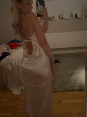 Söker du balklänning? Här en den perfekt rosa klänningen i satin🌸🌸 - Supersnygg ljusrosa långklänning i satin med smala axelband och öppen rygg med snörning. Klänningen har en figurnära passform. Perfekt för bal eller andra speciella tillfällen!