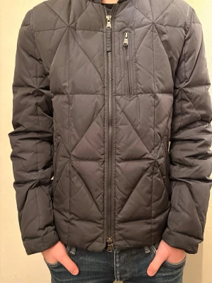 Svart quiltad pufferjacka Morris S - Säljer en svart quiltad pufferjacka från Morris i storlek S. Jackan har dragkedja framtill, bröstficka med zip och Morris-logga på ärmen. Snygg geometrisk quiltning och klassisk passform. Perfekt för kyliga dagar. Kan gå ner i pris vid snabb affär! Hör av dig vid minsta fundering!