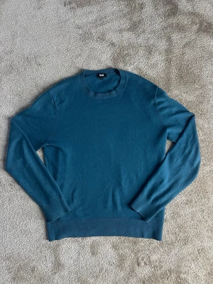 Blå kashmir tröja från Uniqlo - En stilren blå stickad tröja från Uniqlo i storlek S. Tröjan har rund halsringning och är långärmad. Den passar dig som är 168 till 174 cm lång. Priset kan diskuteras.