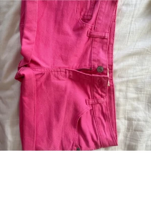 Rosa shorts - Säljer ett par snygga rosa shorts med klassisk femficksdesign och dragkedja framtill. Shortsen har bälteshällor och är tillverkade i ett mjukt bomullstyg som passar perfekt till sommaren. Färgen är riktigt poppig och ger en cool vibe.