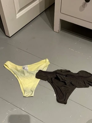 Två bikinibyxor från H&M XS/34 - Säljer två bikinibyxor från H&M i storlek XS. Ena är ljusgul och slät, den andra är brun med volangdetalj upptill. Båda är i mjukt, stretchigt syntetmaterial och perfekta för sommaren.