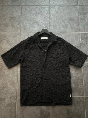 Svart spetsmönstrad skjorta Woodbird - Säljer en svart skjorta från Woodbird använd vid två tillfällen, är som ny. 