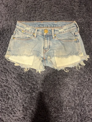 Lågmidjade jeans shorts från Levis - Säljer dessa super snygga jeans shorts från Levis med slitningar. Dem är väldigt lågmidgade där fram, men sitter lite högre upp där bak. Fickorna som hänger ut går att vika in. Jag säljer dem för att de blivit för små. Jag skulle säga att dem passar w23-24. Möjligtvis 25. Jag har 26 och dem knäpper inte i midjan. 