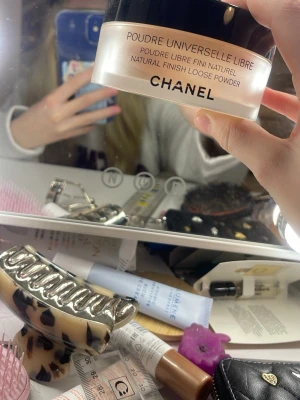 Chanel löspuder Poudre Universelle - Chanel Poudre Universelle Libre är ett transparent löspuder i en stor rund burk med svart lock. Pudret är ljust beige och ger en naturlig finish. Medföljer gör en mjuk puff med Chanel-logga för enkel applicering. Perfekt för att fixera smink och matta ner huden.