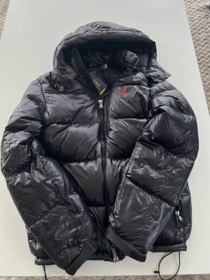 Svart pufferjacka från Polo Ralph Lauren - Säljer en svart pufferjacka från Polo Ralph Lauren med huva och dragkedja, strl S. Skick 9.9/10 bara testad, tagen sitter fof kvar. Online kvitto finns! Hör av er vid minsta lilla fundering, mvh