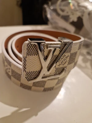 Rutig vit bälte - Snyggt rutig vit bälte i mycket gott skick, längd 110cm, pris kan diskuteras