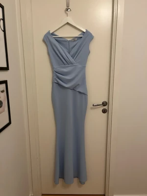 Balklänning  - Säljer en jättefin ljusblå balklänning från Bubbleroom i storlek S. Klänningen har omlottdesign upptill och offshoulder-modell med figurnär passform och dragkedja bak. Perfekt för bal eller student!