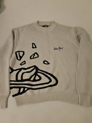 Stickat tröja Broken Planet - Säljer en beige stickad tröja från Broken Planet med svart grafiskt rymdmotiv och broderad logga på bröstet.  Helt ny   Storlek M. Priset kan diskuteras vid snabb affär. Säljer för att den är stor för mig. (Äkta)