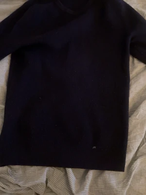 Svart stickad tröja med rund hals - En enkel svart stickad tröja med rund hals och långa ärmar. Perfekt att slänga på sig när det är kyligt ute. Tröjan har en klassisk passform och är gjord i ett mjukt stickat material.