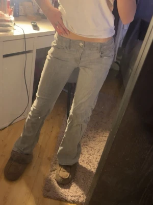 Grå bootcut jeans från Gina Tricot - Säljer ett par gråa jeans från Gina Tricot i storlek 158. De har bootcut-modell med låg midja och klassisk femficksdesign. Jeansen är i mjukt denimtyg och har dubbla knappar framtill. Perfekta för dig som gillar en avslappnad och trendig look.