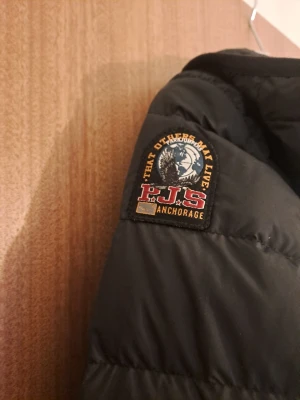 Svart dunjacka Parajumpers XS - Svart dunjacka från Parajumpers i super lättviktsmodell. Jackan har huva, quiltad design och dragkedja i sidan. Märkespatch på ärmen och insida i ljusgrått. Perfekt för dig som vill ha en snygg och funktionell jacka med cool streetkänsla.