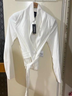 Vit kavaj med bälte från Boohoo - Snygg vit kavaj från Boohoo med långärmad design och markerad krage. Aldrig använt då jag köpte flera plagg för ett speciellt tillfälle🫶