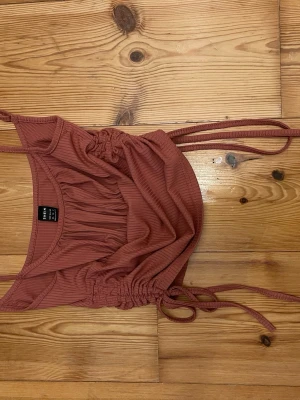 Rostrosa ribbad linnetopp från SHEIN - Trendig rostrosa linnetopp från SHEIN i ribbat material. Toppen har smala axelband och snygga snörningsdetaljer i sidorna som ger en cool look. Perfekt för varma dagar och enkel att styla med jeans eller kjol.