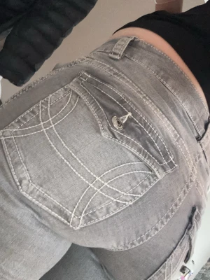 Grå jeans från Perfect Jeans, stl 38 - Säljer ett par grå jeans från Perfect Jeans i storlek 38. Byxorna har snygga kontrastsömmar, fickor med lock och knapp bak samt klassisk femficksdesign. Modellen är rak med lätt bootcut och normal passform. Perfekta till en chill vardagslook.