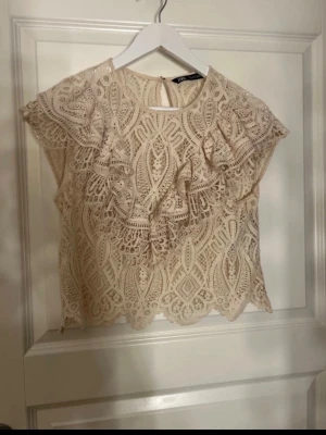 Beige spetsblus Zara - Superfin beige blus från Zara i spets med vackert broderat mönster. Säljer då den inte kommer till användning.