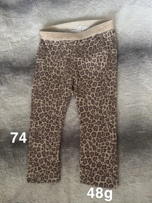 Leopardmönstrade leggings med glitterresår - Snygga leggings med leopardmönster i beige och bruna toner. Byxorna har en glittrig resår i midjan som ger extra stilpoäng. Perfekta för dig som gillar djurmönster och vill ha något bekvämt och trendigt.🌸 Fint använt skick. Storlek 74