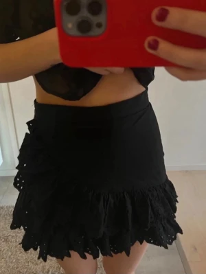 Svart volangkjol med broderade detaljer - Supersöt svart kortkjol med volanger och broderade detaljer längst ner och på ena sidan. Den är i storlek xs från Zara. Helt slutsåld!! 💗💗