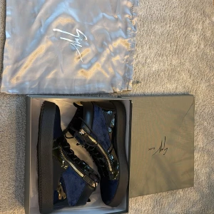 Giuseppe zanotti  - Snygga blå sneakers från Giuseppe Zanotti med svarta detaljer och dragkedja på sidan. Skorna har en unik design med en kombination av glansigt och matt material. Perfekta för att ge din outfit en extra edge.