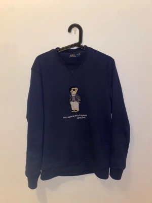 Ralph lauren polo bear tröja - Säljer en mörkblå crewneck från Polo Ralph Lauren med broderad Polo Bear på bröstet. Väldigt fin marinblå färg. Tröjan är helt felfri och i väldigt bra skick. Pris är diskuterbart och kontakta mig om frågor!😊