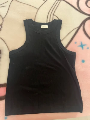 Svart och brun ribbad linnetopp - Två stilrena ribbade linnetoppar från weekday basics i svart och brun. Modellen är ärmlös med rund hals och croppad passform, perfekt för att matcha med jeans eller kjol. Materialet är mjukt och stretchigt bomull som sitter skönt mot kroppen.