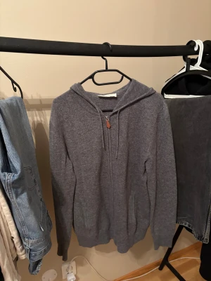 Grå hoodie i kashmir från Sayless - Mjuk och stilren grå hoodie från Sayless i kashmir. Tröjan har huva, dragkedja framtill med läderdetalj och två fickor. Perfekt för dig som gillar chill och enkel stil med premiumkänsla. Långärmad och loose passform.