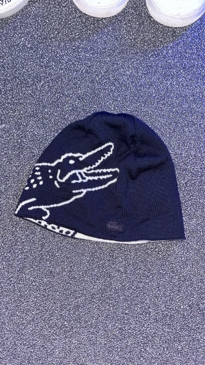Lacoste mössa - Använder inte denna feta lacoste beanie längre så bättre att den kommer till någon annan! Cond 8/10 knappt använd
