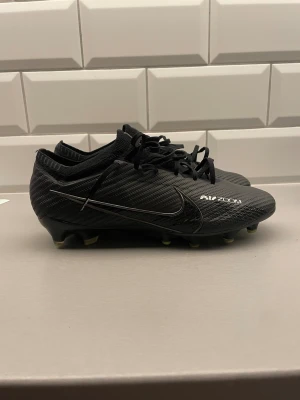 Nike Mercurial Vapor 15 Elite Ag Air Zoom fotbollsskor - Ett par svarta Nike mercurial vapor 15 elite ag. De är konstgräsdobbar. Nypris ca 3000. I perfekt skick, endast använda några få gånger. Hör av dig om du behöver fler bilder eller har några frågor! Storlek 40,5 (25,5cm) 