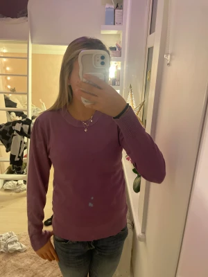 Lila stickad tröja från Saint Tropez - Snygg lila stickad tröja från Saint Tropez i storlek S. Tröjan har rund hals, ribbade muddar och långärmad passform. Perfekt att matcha med jeans eller kjol för en chill look. Materialet är mjukt och skönt mot huden.