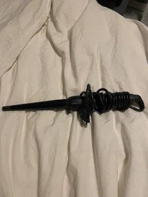 CeraWand Locktång - Locktång från CeraWand med konisk stav för naturliga lockar. Svart design, sladd med EU-kontakt. Produkten ser ut att vara i gott skick med mindre tecken på normalt bruk. Perfekt för styling av hår hemma eller på resan.