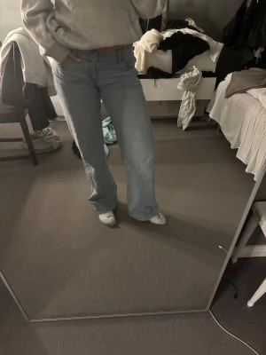 Ljusblåa wide jeans - Säljer ett par ljusblåa jeans med breda ben och klassisk femficksdesign. Jeansen har normal midja och är tillverkade i mjukt denimtyg som ger en avslappnad och trendig look. Perfekta för dig som gillar en loose och bekväm passform.
