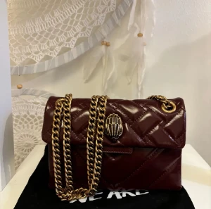 Vinröd Kurt Geiger - Jätteee fin Kurt Geiger väska med guldfärgad kedja, vilket jag tycker gör en super fin detalj!! Använd ca 5 gånger och säljs endast för att jag tyvärr inte får så mycket användning av den som jag önska💓