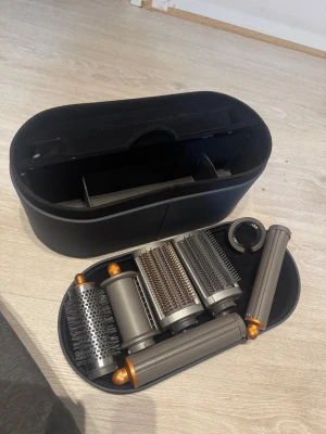 Dyson Airwrap Complete - Dyson Airwrap Complete med flera stylingtillbehör och originalförvaringsväska. Flera borstar och locktillbehör ingår. Produkten ser ut att vara i mycket gott skick utan synligt slitage. Perfekt för att skapa olika frisyrer med minimal värmeskada.