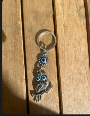 Nyckelring med uggla och blå ögon - Unik nyckelring i silverfärgad metall med en detaljrik uggla som har två blå evil eye-ögon. Ovanför ugglan sitter ytterligare en blå evil eye-berlock. Perfekt accessoar för dig som gillar symbolik och coola detaljer.